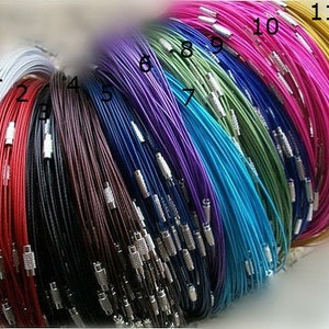 May include: A collection of 11 different colored cords with silver clasps. The cords are arranged in a rainbow pattern, starting with white and ending with gold.