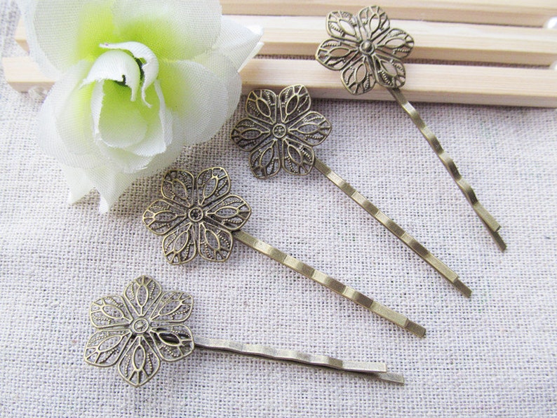 May include: Five bronze hair clips with a delicate floral design. Each clip features a detailed flower shape with a decorative openwork pattern.