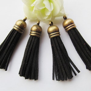 May include: Five black suede tassels with antique gold metal tops. The tassels are approximately 2 inches long.