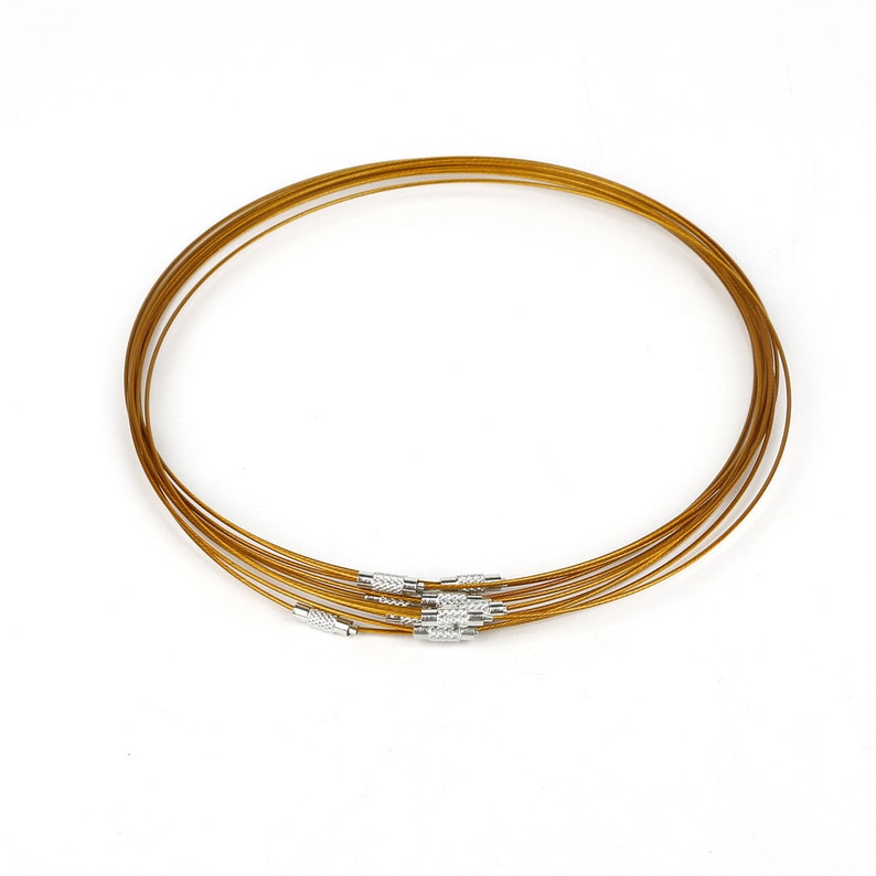 May include: A set of six gold-colored metal necklace chains with silver clasps. The chains are stacked on top of each other.