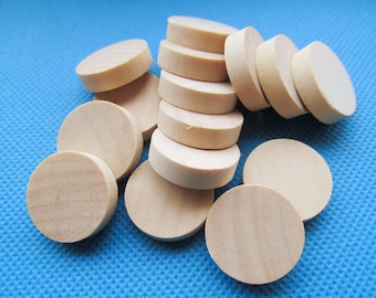 May include: A pile of round, unfinished wooden discs in various sizes, stacked and scattered on a blue background.