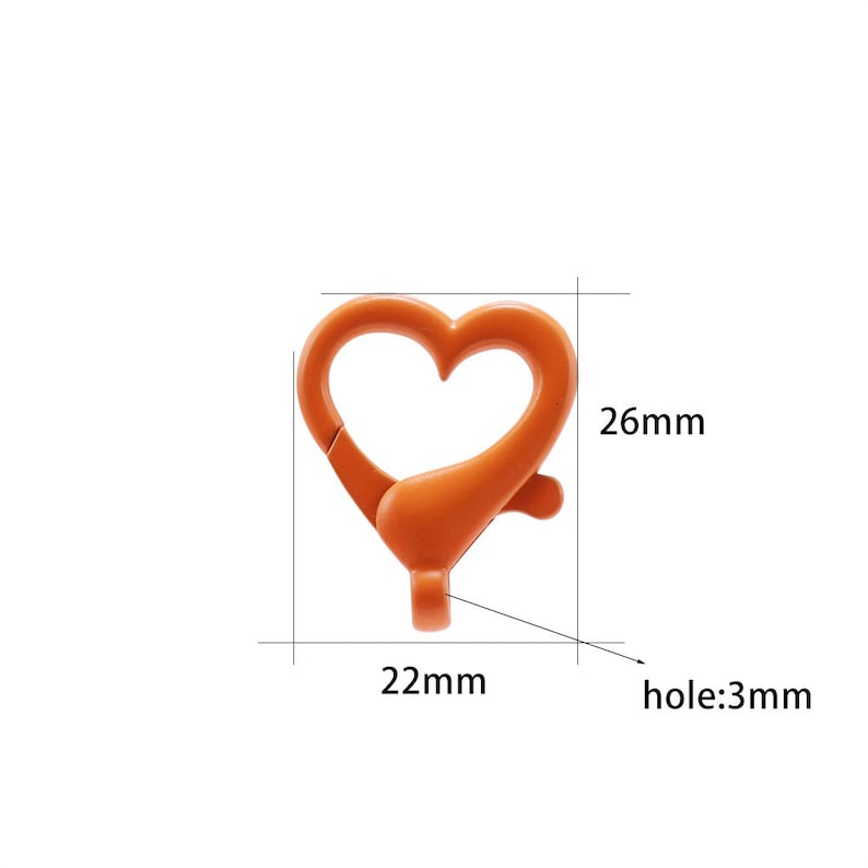May include: Orange heart-shaped metal clasp with a 3 mm hole. The clasp measures 22 mm wide and 26 mm tall.