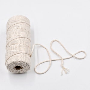 May include: A roll of natural cotton twine with a length of twine extending from the roll. The twine is a light cream colour.