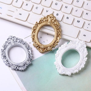 May include: Three ornate oval picture frames in gold, silver, and white. The frames have a decorative, intricate design.