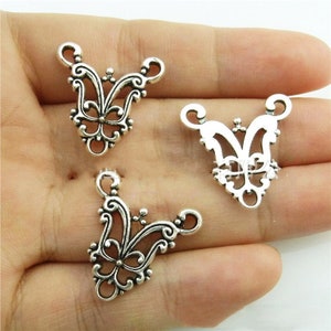 May include: Three silver-toned metal butterfly-shaped pendant connectors with intricate filigree designs. Each connector has three loops for attaching to jewelry.