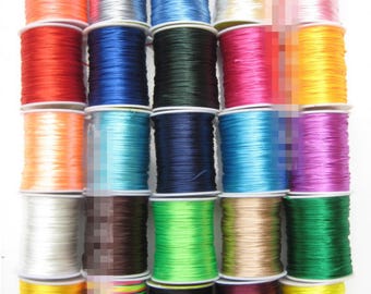 May include: Assortment of 24 spools of colourful elastic cord, each wound on a white plastic spool. The cords are in various colours, including red, blue, green, yellow, orange, purple, pink, white, black, and brown.