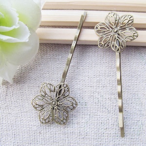 May include: Two gold-toned hair clips with a delicate floral design. Each clip features a detailed, openwork flower shape.