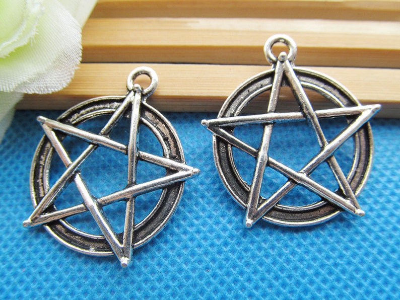 May include: Two silver-toned metal charms in the shape of a pentagram, each with a circle around the star. The charms are perfect for jewelry making or crafting.