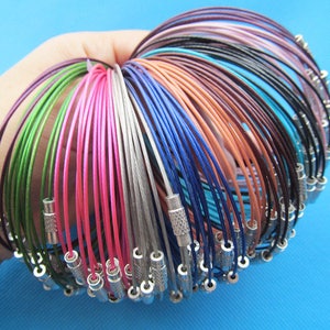 Può includere: Un mazzo di braccialetti in filo metallico colorati con chiusure argentate. I braccialetti sono disposti in cerchio e sono di diversi colori, tra cui rosa, blu, verde e viola.