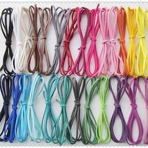 May include: A collection of colorful suede cords in various shades, including black, white, brown, gray, red, pink, orange, and yellow. Additional colors are blue, teal, green, and purple. The cords are bundled together, showcasing their vibrant hues.