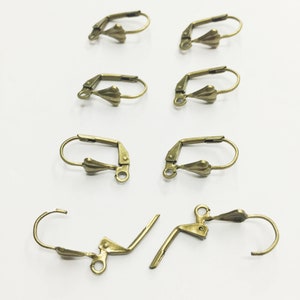 May include: A set of eight gold-toned earring hooks. The hooks are made of metal and have a teardrop-shaped design. The hooks are designed to be used with earrings.
