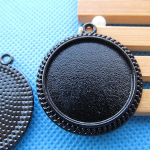May include: Two black metal round pendant trays with a beveled edge. One tray has a smooth surface and the other has a textured surface.