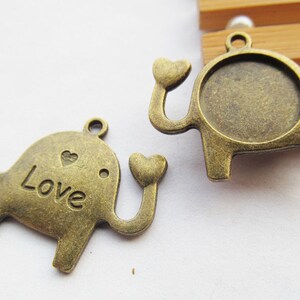May include: Two antique gold-toned elephant charms with a heart design. One charm has the word "Love" engraved on it, and the other has a round, open space for a cameo or photo.