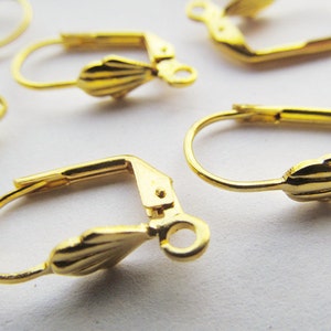 May include: Gold-toned earring hooks with a scalloped design. The hooks are made of metal and have a spring-loaded closure.