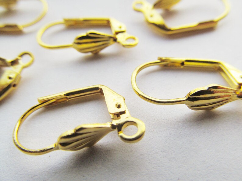 May include: Gold-toned earring hooks with a scalloped design. The hooks are made of metal and have a spring-loaded closure.