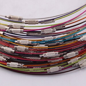 May include: A close-up of a stack of colorful metal cable chains with silver clasps. The chains are arranged in a circular pattern, with the clasps facing outward. The chains are a variety of colors, including red, orange, yellow, green, blue, purple, and black.