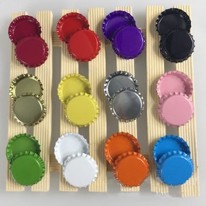 Peut inclure: Assortiment de 12 paires de capsules de bouteilles de différentes couleurs, dont rouge, violet, noir, or, jaune, argent, rose, blanc, vert, orange et bleu. Chaque capsule est en métal et a une finition lisse et brillante.