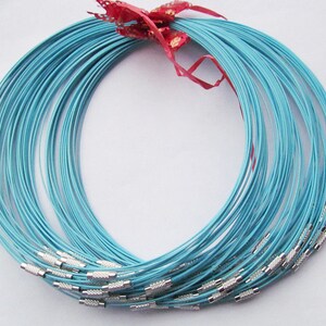 Puede incluir: Un conjunto de cadenas de collar de metal azul claro con cierres plateados. Las cadenas est&aacute;n dispuestas en c&iacute;rculo.