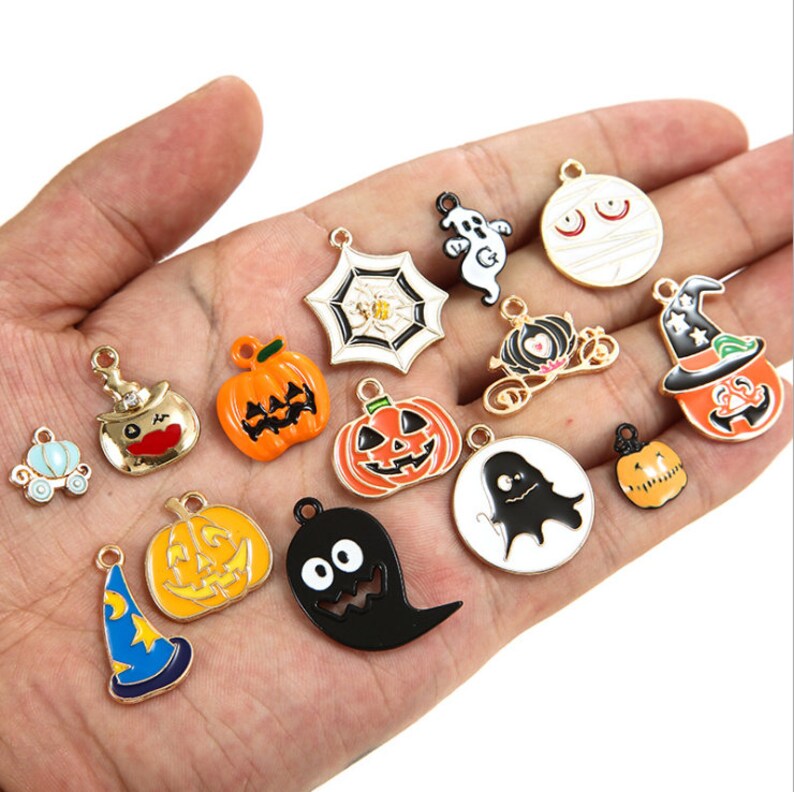 May include: Assortment of Halloween-themed charms, including pumpkins, ghosts, witches hats, a spider web, and a mummy. The charms are made of metal and have a gold finish.