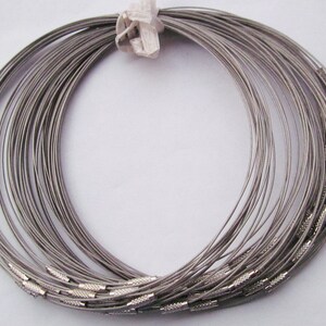 Puede incluir: Un conjunto de collares de choker de metal plateado con cierre de broche. Los collares est&aacute;n dispuestos en c&iacute;rculo.