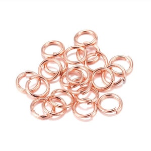 May include: A pile of rose gold jump rings, a type of jewelry finding used for connecting chains, cords, and other jewelry components.