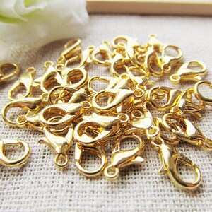 Puede incluir: Un mont&oacute;n de cierres de langosta de metal dorado, com&uacute;nmente utilizados para la fabricaci&oacute;n de joyas.
