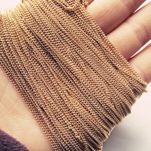 May include: A close-up of a gold chain, showing the intricate details of the links. The chain is coiled and lying on a hand.