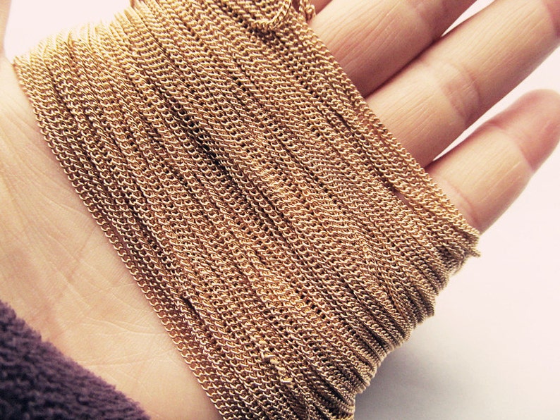 May include: A close-up of a gold chain, showing the intricate details of the links. The chain is coiled and lying on a hand.