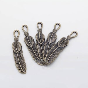 May include: Five antique bronze feather charms with a loop at the top for attaching to jewelry or other crafts.