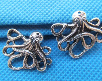 May include: Two silver-toned octopus charms with detailed tentacles. The octopus charms are on a blue textured background.