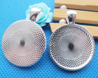 May include: Two silver-toned round pendant trays with a swirl pattern. The trays have a loop at the top for attaching a chain or cord.