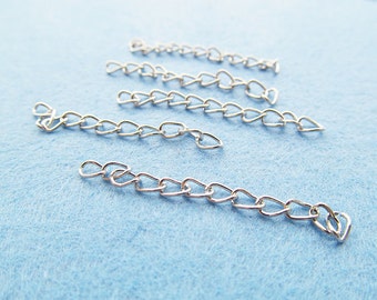 Puede incluir: Seis eslabones de cadena de plata en forma de corazón sobre un fondo azul claro.