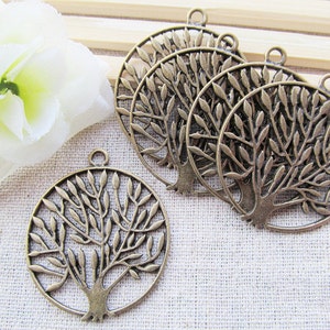 Pode incluir: Cinco pingentes de árvore da vida em metal bronze antigo com um design circular e um laço para pendurar. Os pingentes são intrincadamente detalhados com um tronco de árvore e galhos com folhas.