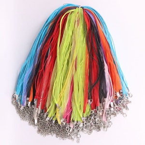 May include: A bundle of colorful ribbon cords with silver clasps. The cords are in various colors, including red, blue, green, yellow, and pink.