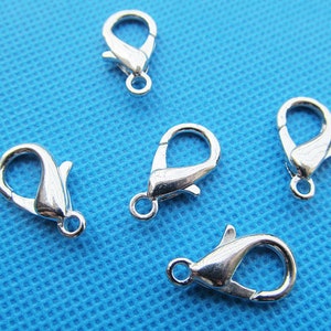 May include: Five silver-toned lobster clasps, a type of fastener used in jewellery making.