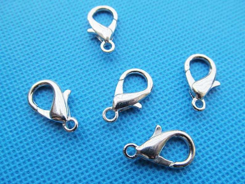 May include: Five silver-toned lobster clasps, a type of fastener used in jewellery making.