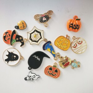 May include: Assortment of Halloween-themed charms, including pumpkins, ghosts, bats, witches hats, and a spider web. The charms are made of metal and have a gold finish.