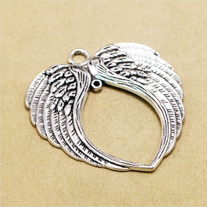 May include: Silver-toned metal pendant shaped like a heart with angel wings. The wings are detailed with feathers and have a textured finish.