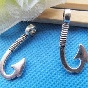 Op de afbeelding: Twee zilverkleurige metalen vishaakbedels met een textuurontwerp. De haken zijn ongeveer 5 cm lang.