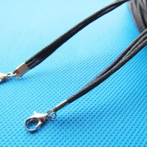 Puede incluir: Cordón negro con dos cierres de langosta plateados. El cordón está hecho de varios hilos de cordón negro delgado.