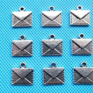 May include: Ten silver-toned metal envelope charms with a loop at the top for attaching to jewelry or crafts. The charms are about 1 inch in size and have a detailed design.