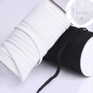 May include: Two spools of elastic cord, one white and one black, are wound around cardboard cores. The elastic cord is used for sewing and crafting projects.