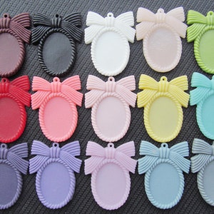 May include: Assortment of 16 oval-shaped plastic picture frames with a bow design. The frames are in various colors, including red, pink, purple, blue, green, yellow, brown, black, and white.