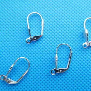 May include: Four silver earring clip-on findings. The findings are made of metal and have a smooth finish.