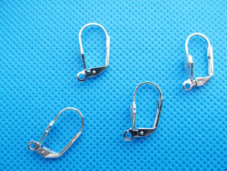 May include: Four silver earring clip-on findings. The findings are made of metal and have a smooth finish.
