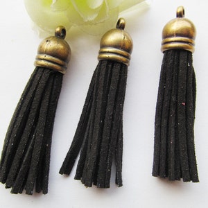 May include: Three black suede tassels with gold metal tops. The tassels are approximately 2 inches long.