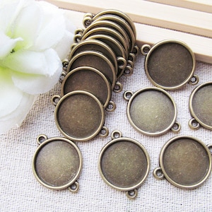 Puede incluir: Un conjunto de 10 bandejas redondas para colgantes de metal de color bronce antiguo con tres bucles en cada una. Las bandejas son perfectas para añadir un toque vintage a los proyectos de elaboración de joyas.
