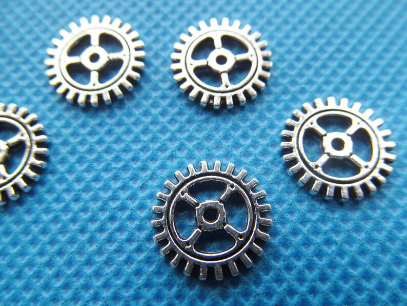 May include: Six silver metal gears of varying sizes on a blue textured background.