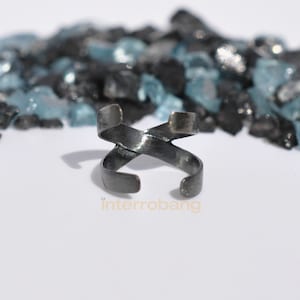 May include: A silver-toned ring with a twisted design. The ring is made of metal and has a smooth finish.