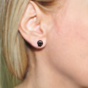 May include: A pair of black skull stud earrings. The earrings are small and simple, and they are a great way to add a touch of edgy style to any outfit.